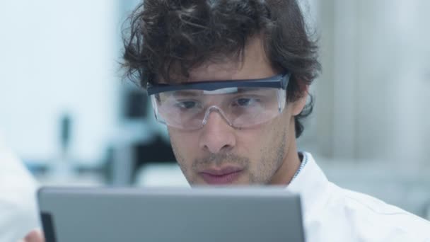 Ethnie latine Scientifique en lunettes de sécurité utilisant un ordinateur tablette en laboratoire . — Video