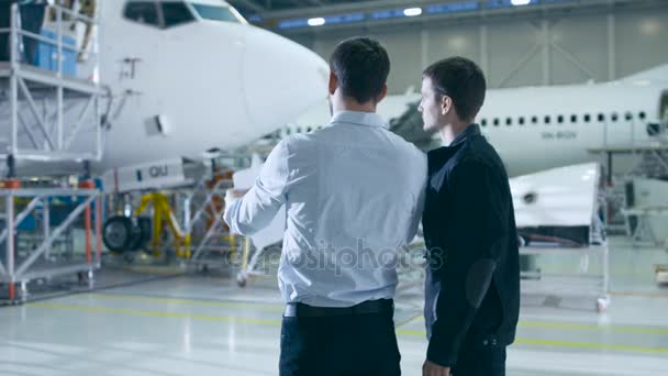 Trabalhador e Engenheiro de Manutenção de Aeronaves Conversando. Olhando para o avião . — Vídeo de Stock