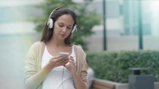 Ung attraktiv kvinna gå på gatorna och lyssnar musik. Modern stadsmiljö. — Stockvideo