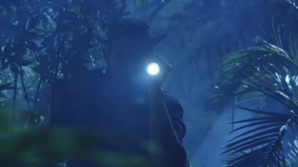 Avonturier in Hat wandelen door Jungle bos in de nacht. Met behulp van de zaklamp — Stockvideo