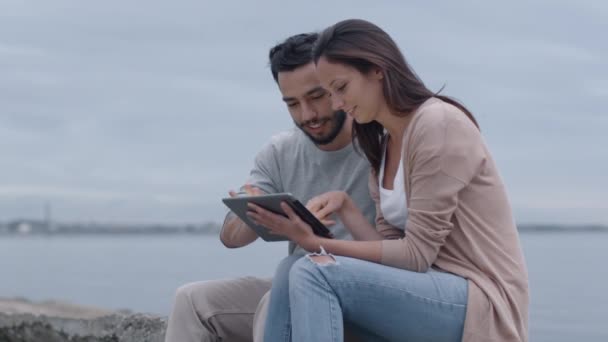 Sourire et rire Couple attrayant à l'aide d'un ordinateur tablette en plein air . — Video