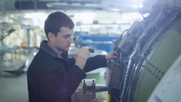 Flugzeugwartungsmechaniker inspiziert mit Taschenlampe Flugzeugdüsenmotor im Hangar — Stockvideo