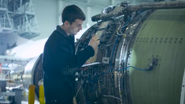 Mechanik statku powietrznego inspekcji i pracę na silnik odrzutowy samolot w hangarze — Wideo stockowe