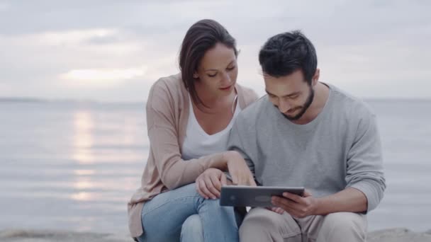 Sorrindo e rindo casal atraente usando Tablet Computer ao ar livre . — Vídeo de Stock