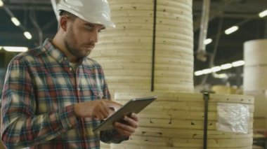 İşçi kereste fabrikası depoda bir tablet bilgisayar kullanıyor.