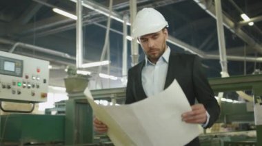 İşadamı projeleri üzerinde bir plan bir Sanayi Fabrikası'nda arıyor.