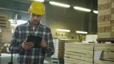 İşçi kereste fabrikası depoda bir tablet bilgisayar kullanıyor.