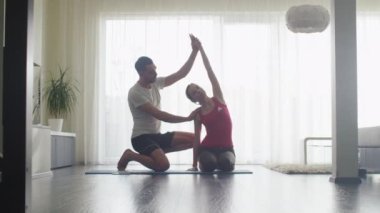 Kadın ve germe yapan erkek ve birlikte oturma odasında evde Fitness.