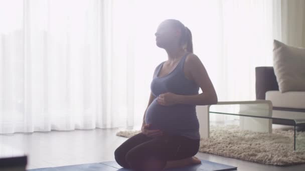 Mujer embarazada joven haciendo estiramiento y fitness en la sala de estar en casa . — Vídeo de stock