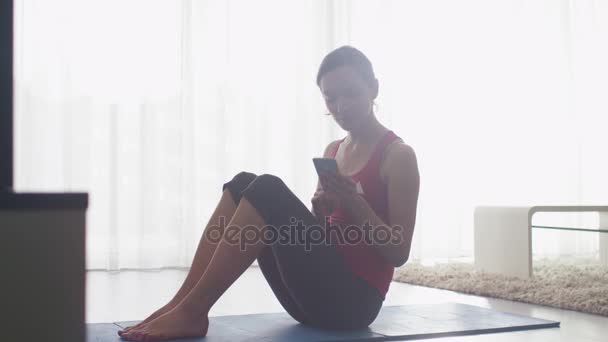 Νεαρή γυναίκα να κάνει το τέντωμα και το γυμναστήριο στο σαλόνι στο σπίτι. — Αρχείο Βίντεο