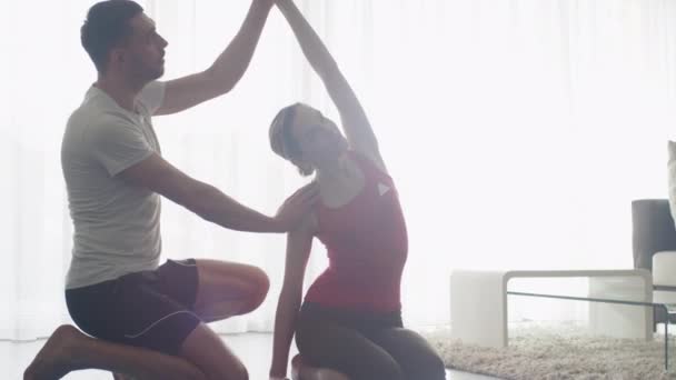 Donna e uomo che fanno stretching e fitness insieme in salotto a casa . — Video Stock