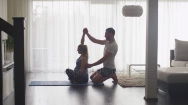 Hamile kadın ve germe yapan erkek ve birlikte oturma odasında evde Fitness.