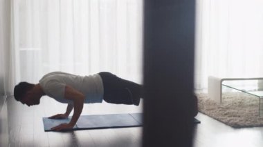 Yakışıklı adam egzersiz ve yapıyor Push ups oturma odasında evde.