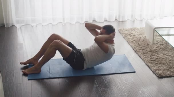 Hombre guapo haciendo ejercicio en la sala de estar en casa . — Vídeo de stock