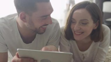 Erkek ve kadın yerde döşeme ve eğlence için Tablet kullanma.