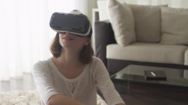 Oturma odasında VR kulaklık giyen kadın.