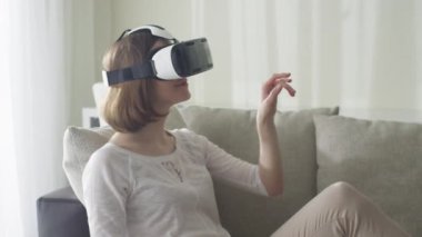 Oturma odasında VR kulaklık giyen kadın.