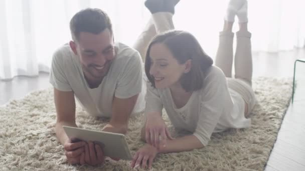 Мужчина и женщина лежат на полу и используют планшет для развлечения . — стоковое видео