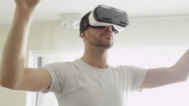 Oturma odası VR kulaklık giyen adam. Hareketleri el ile kullanarak.