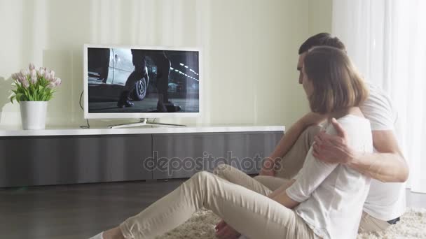 Пара просмотров боевика по телевизору в гостиной — стоковое видео