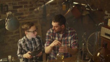 Baba ve oğul evde bir garaj bir tablet bilgisayar denetlenirken kimya deneyleri yapıyoruz.