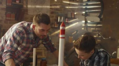 Baba ve oğul evde bir garaj bir oyuncak roket modelleme.