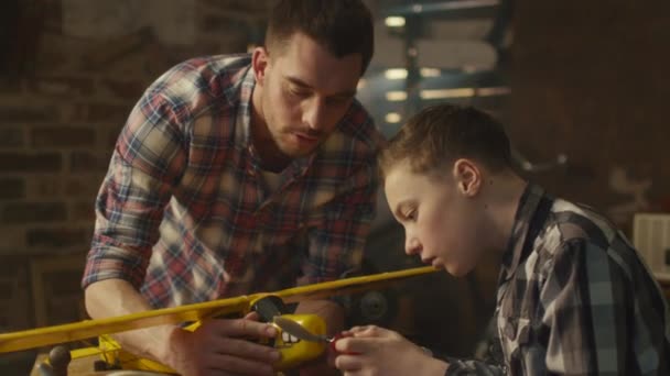 Pai e filho estão modelando um avião de brinquedo em uma garagem em casa . — Vídeo de Stock