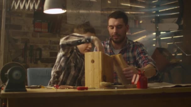 Vader en zoon zijn het maken van een houten nesten box in een garage bij u thuis. — Stockvideo