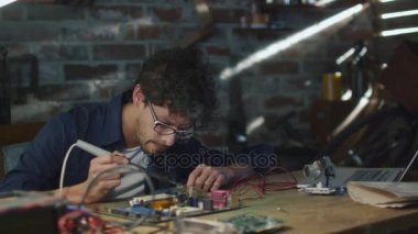 Öğrenci elektronik eğitim ve bir devre kartı bir garajda lehimleme.