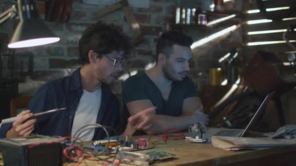 Dva studenti studují elektroniky a pájení v garáži. — Stock video