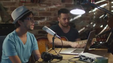 İki genç adam şarkı ve ev stüdyosunda bir garaj bir şarkı kaydederken gitar çalmak.