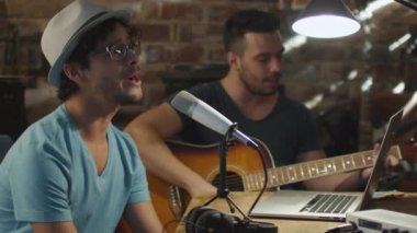 İki genç adam şarkı ve ev stüdyosunda bir garaj bir şarkı kaydederken gitar çalmak.