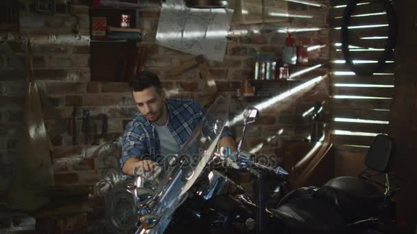 Člověk je čištění a leštění Chromu objektů na svém motocyklu v garáži. — Stock video