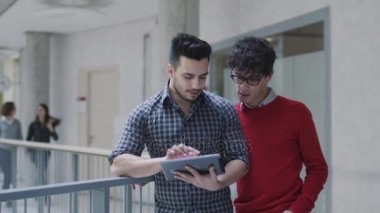 Genç kız ve erkek öğrenciler bir üniversitede bir tablet bilgisayar kullanıyor.