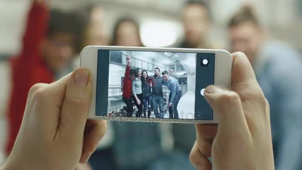 Eerste beelden van de mening van een persoon die een foto van studenten met een smartphone. — Stockvideo