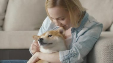 Mutlu sarışın kadın yanındaki bir kanepe evde beslenen hayvan köpek vasıl ev ile oynuyor.
