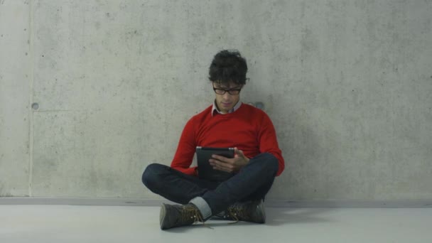 Giovani studenti è seduto sul pavimento in un corridoio del college e utilizzando un computer tablet . — Video Stock