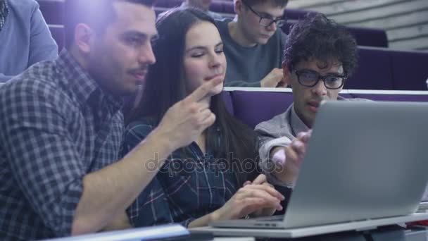 Női és férfi tanulócsoport ül a főiskolán tantermi és látszó-on egy laptop számítógép. — Stock videók