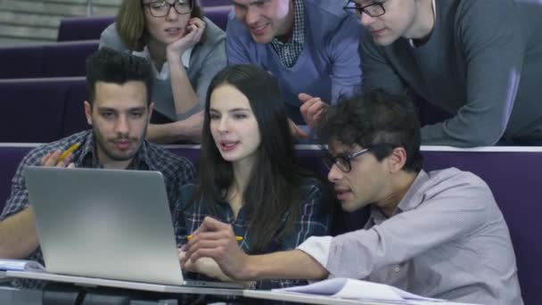 Skupina studentů, ženské a mužské sedí ve škole ve třídě a při pohledu na přenosný počítač. — Stock video