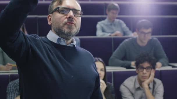 Profesor universitario está enseñando una clase de estudiantes multiétnicos mientras señala el escritorio con un marcador . — Vídeos de Stock
