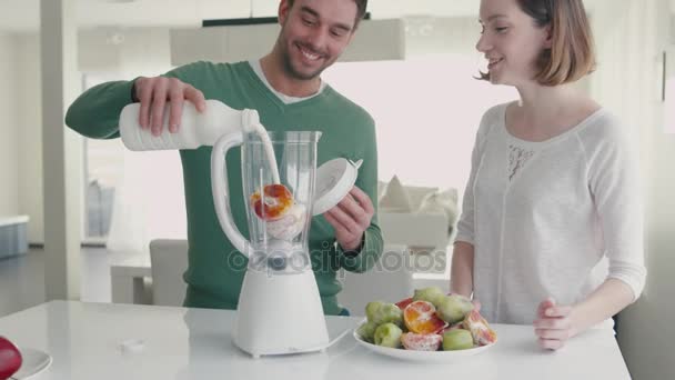 Gelukkige romantisch paar zijn het maken van smoothies in de blender in de keuken thuis. — Stockvideo