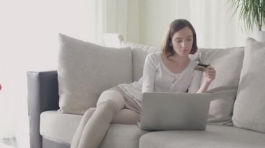 Genç kadın evde kanepede oturan ve alışveriş online kredi kartı ile.