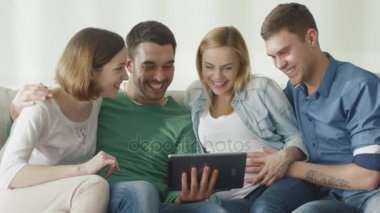 Arkadaşlar evde kanepede oturan ve eğlence için tablet kullanma. 