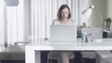 Kadın evde bir dizüstü bilgisayarda çalışıyor.