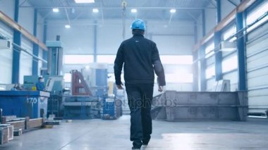 Endüstriyel tesisler ile yürüyen bir kask fabrika işçisi görüntülerini izleyin.