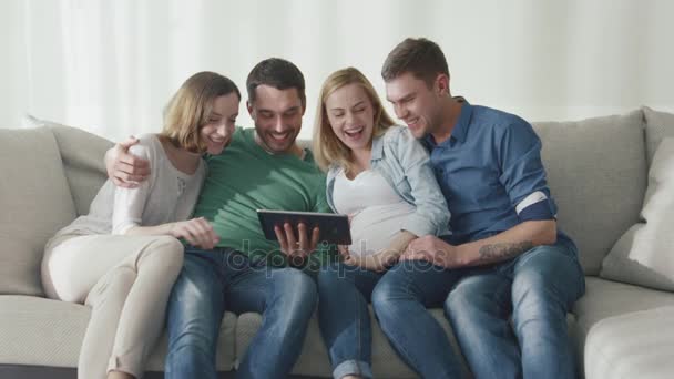 Przyjaciele są siedzi na kanapie w domu i za pomocą tabletu dla rozrywki. — Wideo stockowe