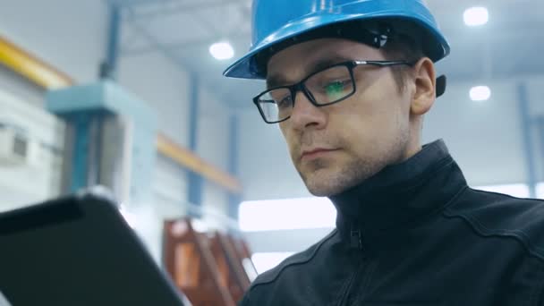 Factory worker in a hard hat is using a tablet computer. — Stock Video