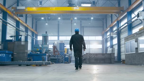 Travailleur d'usine dans un casque dur marche à travers les installations industrielles . — Video