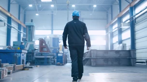 Siga imagens do trabalhador da fábrica em um chapéu duro que está andando através de instalações industriais . — Vídeo de Stock