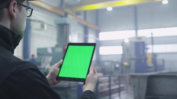 Μήκος σε πόδηα ενός tablet με οθόνη πράσινο mock-up που χρησιμοποιείται από έναν εργαζόμενο σε βιομηχανικό περιβάλλον σε ένα εργοστάσιο. — Αρχείο Βίντεο